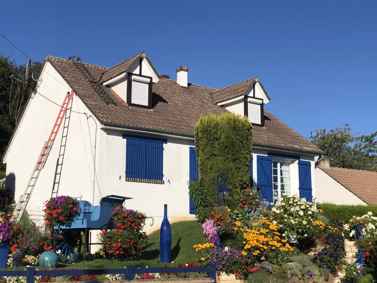 Maison aux volets bleus avec sa toiture en tuiles propre après démoussage par Renaud Rénov en Eure-et-Loir (28)