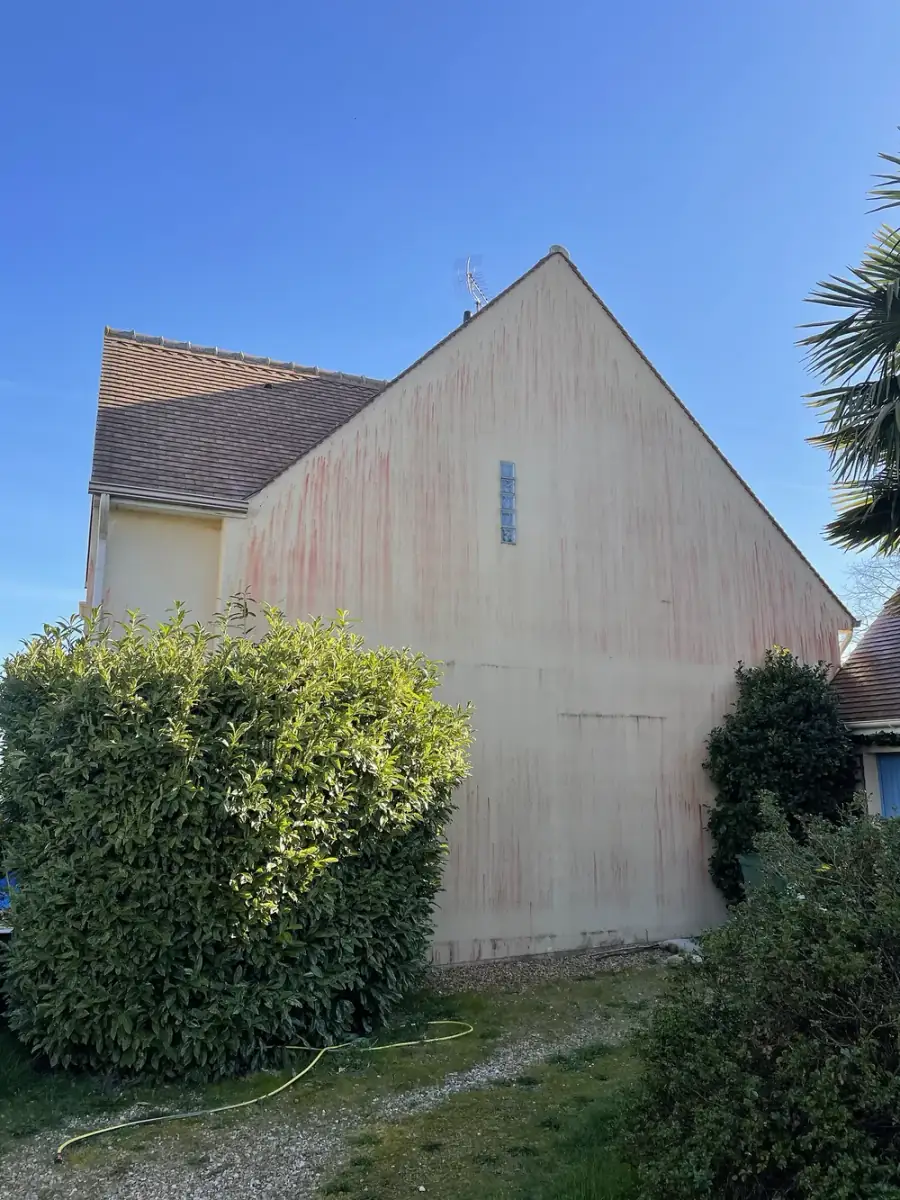 Pignon marqué de traînées rouges avant nettoyage de façade dans le 28